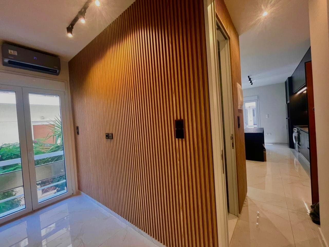 Oak slat feature wall with track lighting in a renovated apartment