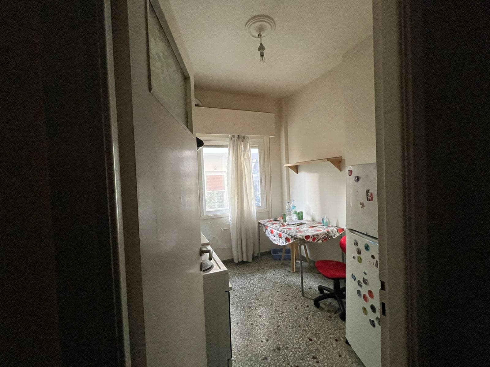 Η στενή κουζίνα πριν την ανακαίνιση, με μωσαϊκό δάπεδο και μικρό τραπέζι