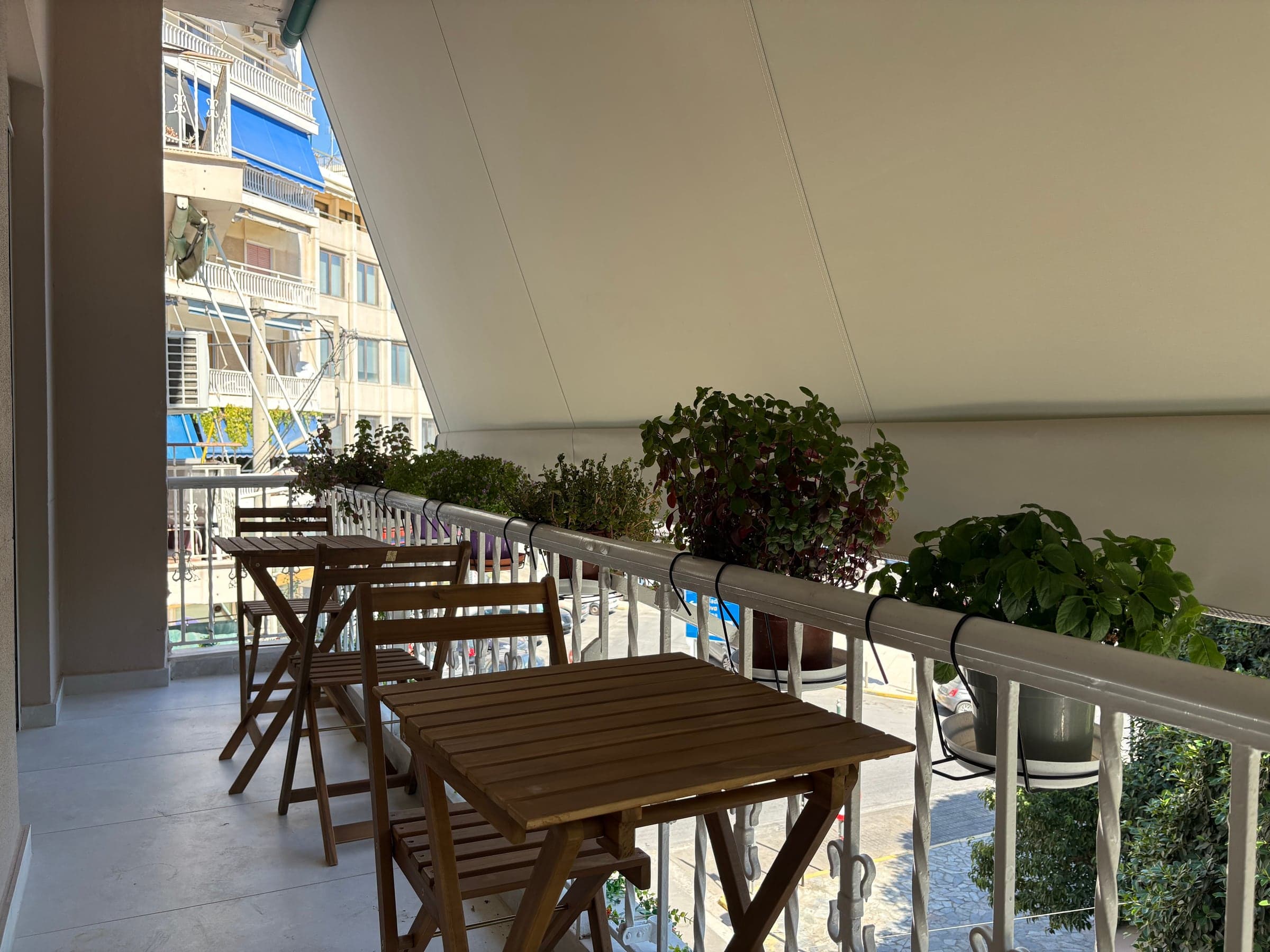 Renovated apartment balcony in Greece with planters and wooden table